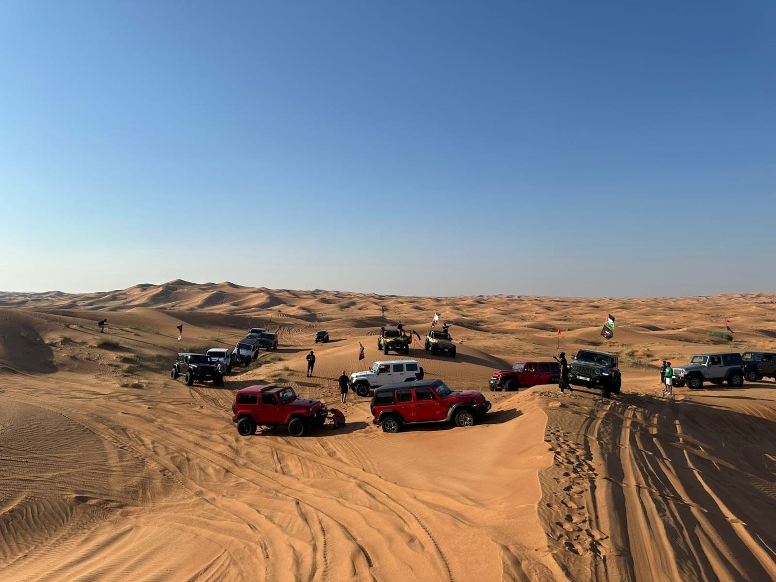 Jeeps spread along a dune ridge at dusk