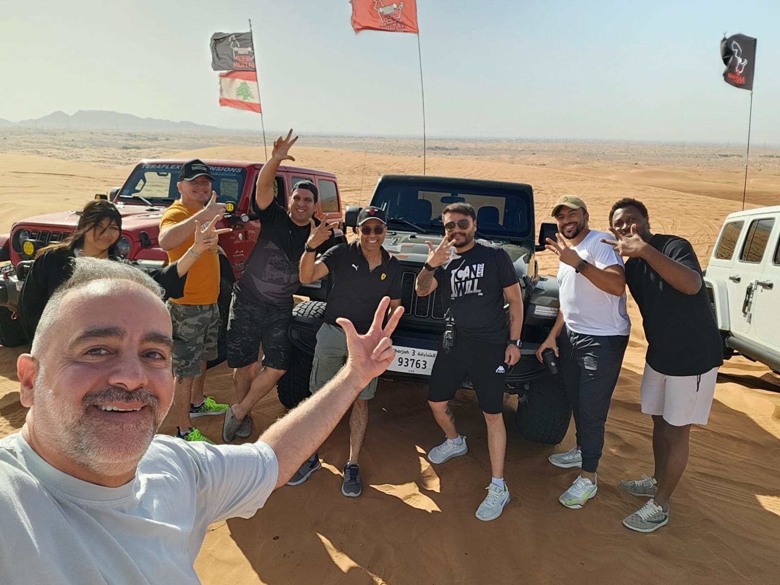 Members waving from beside their Jeeps in the desert